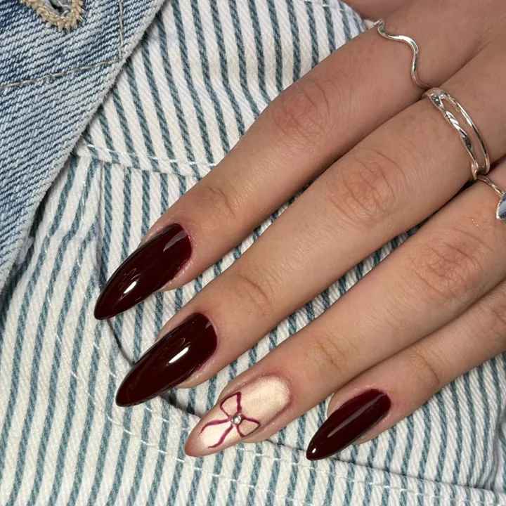 Unhas em gel vinho com detalhe de laço